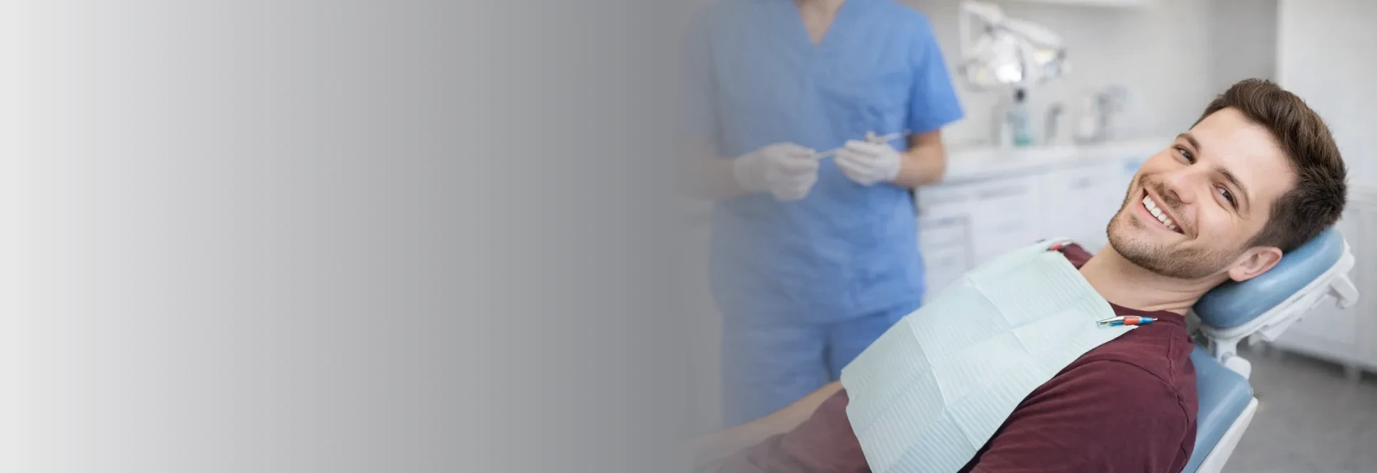 Smiling man reclining in a dental chair with a hygienist beside him